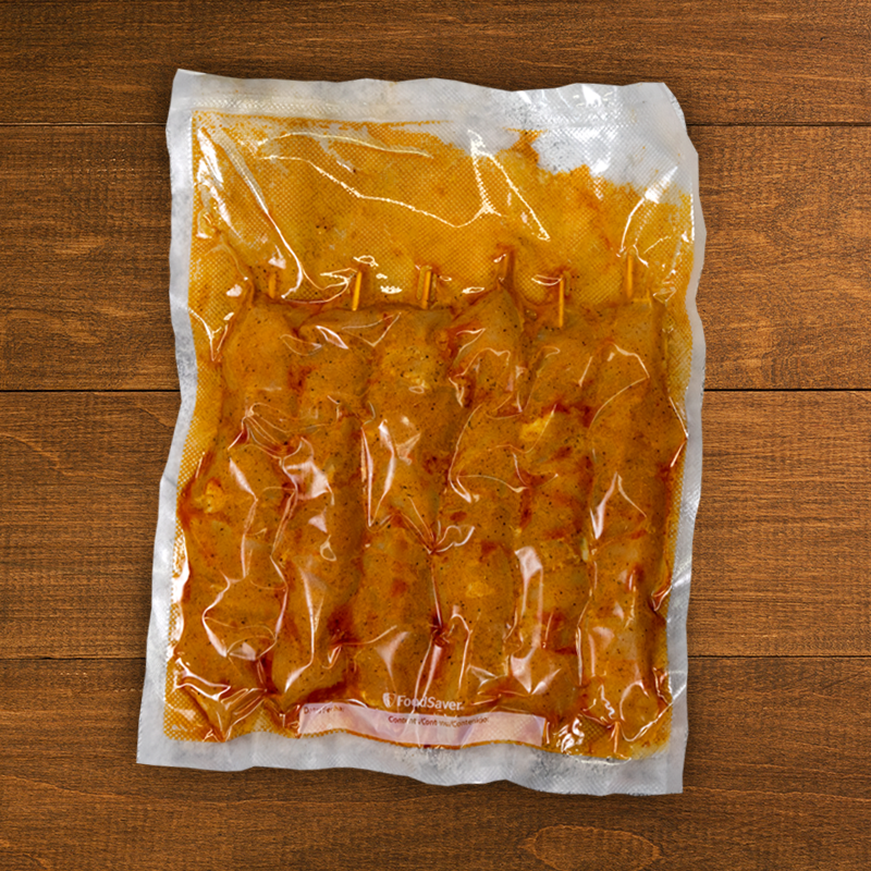 A vacuum-sealed package of succulent, halal-marinated Frozen Chicken Shish Tawook by Tayybeh rests invitingly on a wooden surface.