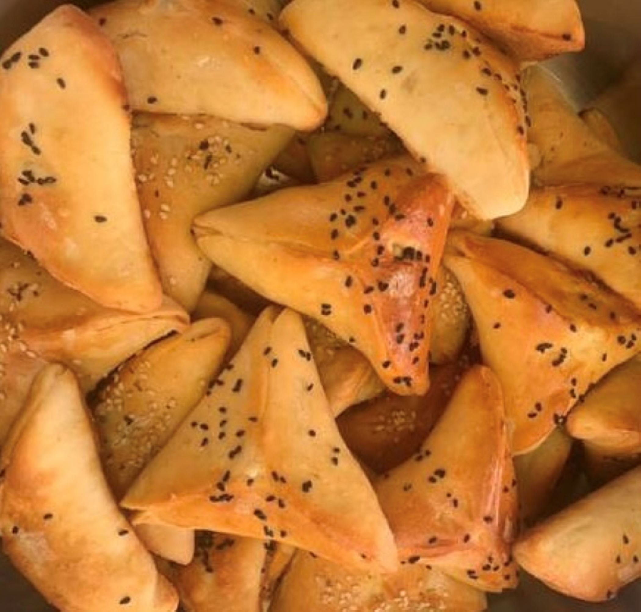 A stack of golden-brown triangular pastries, sprinkled with black sesame seeds and evocative of nut-free homestyle cheese delights, Tayybeh's Frozen Cheese Fatayer (6 pieces).