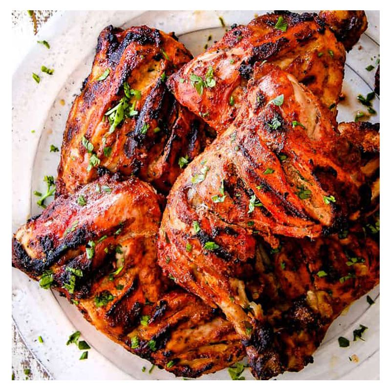 Msahhab Chicken by Tayybeh features grilled chicken thighs seasoned with aromatic spices and garnished with chopped herbs, beautifully presented on a white plate.