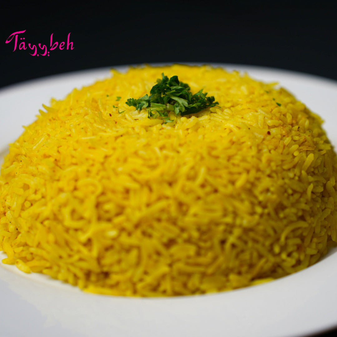 A plate of Tayybeh's flavorful Mandi Rice, expertly garnished with fresh green herbs, served on a white dish against a dark background.