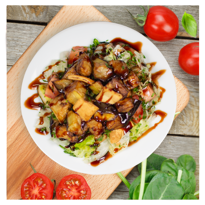 An Eggplant Fattoush Salad by Tayybeh, elegantly arranged on a wooden board, is enhanced with a touch of pomegranate molasses and accompanied by fresh tomatoes and spinach leaves.