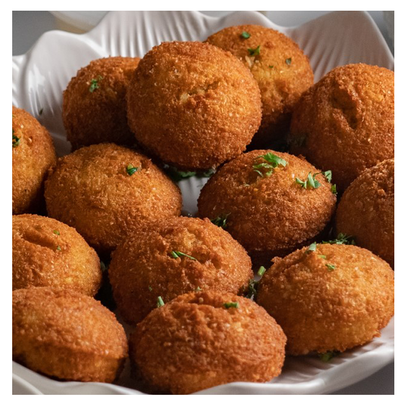 A plate of golden-brown fried Tayybeh Falafel garnished with chopped parsley, perfect for pairing with a creamy hummus dip.