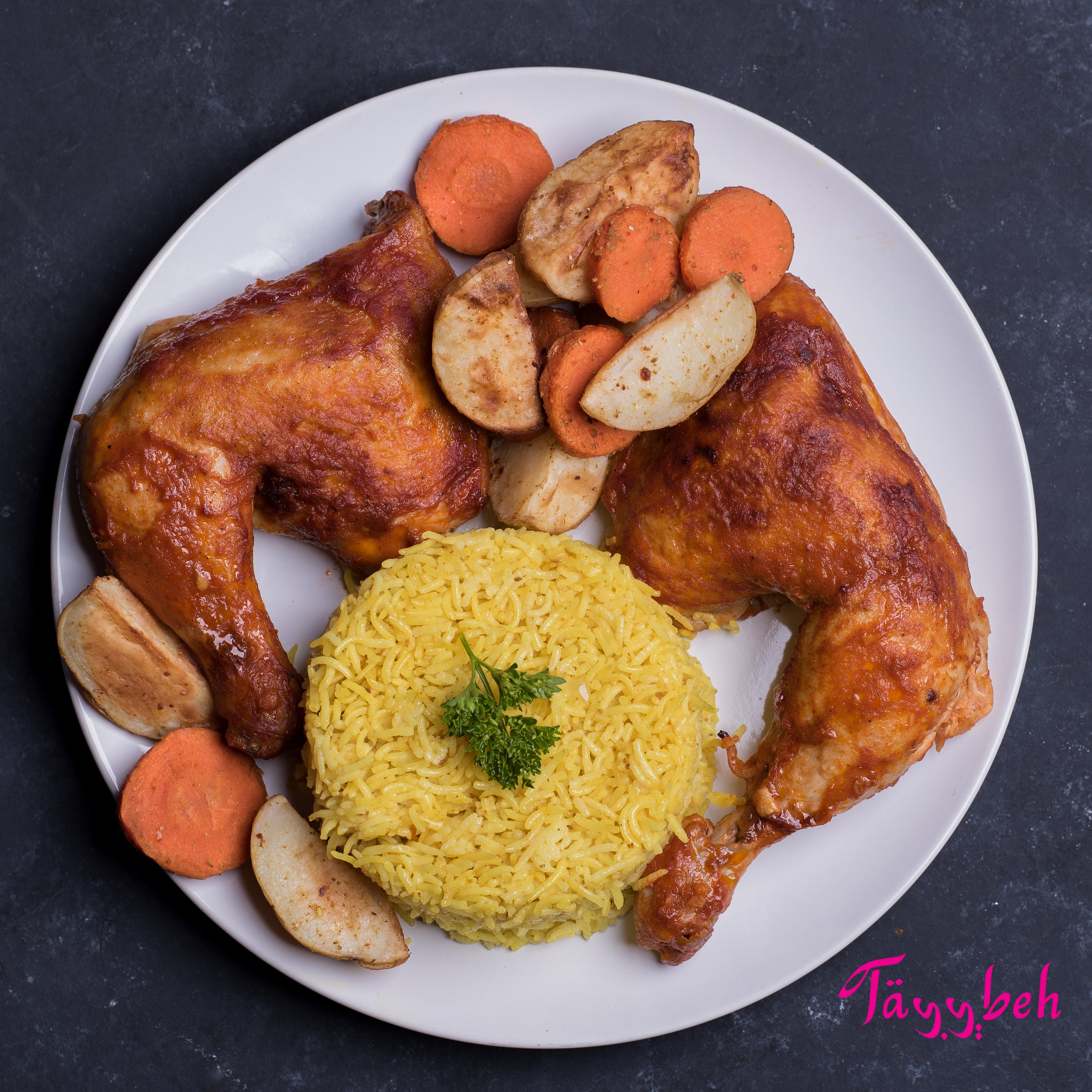 Introducing the Tayybeh Mesahhab Roast Chicken Frozen Dinner for Two: savor succulent roast chicken legs on a bed of fragrant Basmati rice, garnished with herbs, and complemented by roasted carrot and potato slices. A delightful ready-to-eat meal experience.